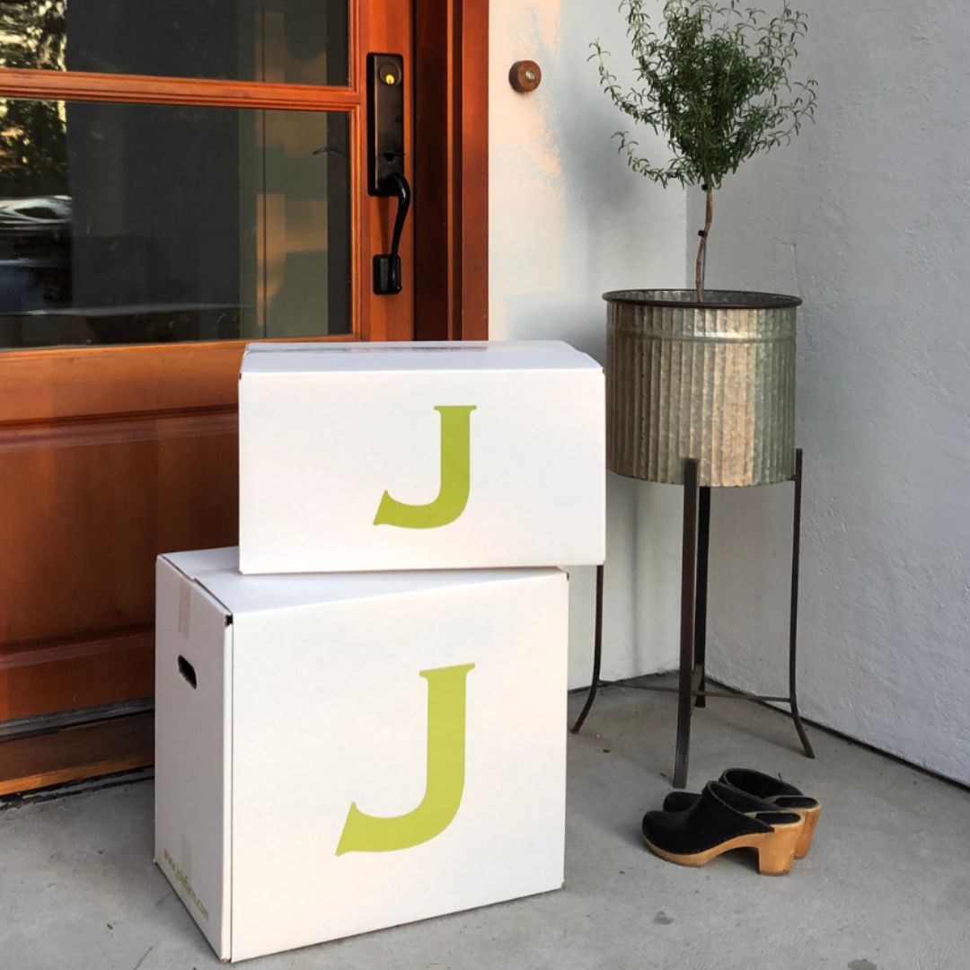 2 delivered JOIE boxes stacked on house entryway.