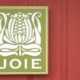 Green JoieFarm sign on red farmhouse