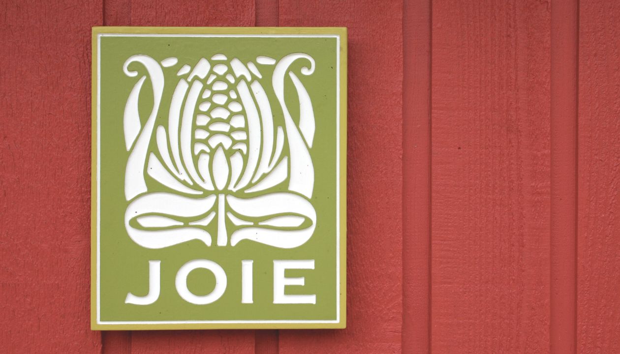 Green JoieFarm sign on red farmhouse