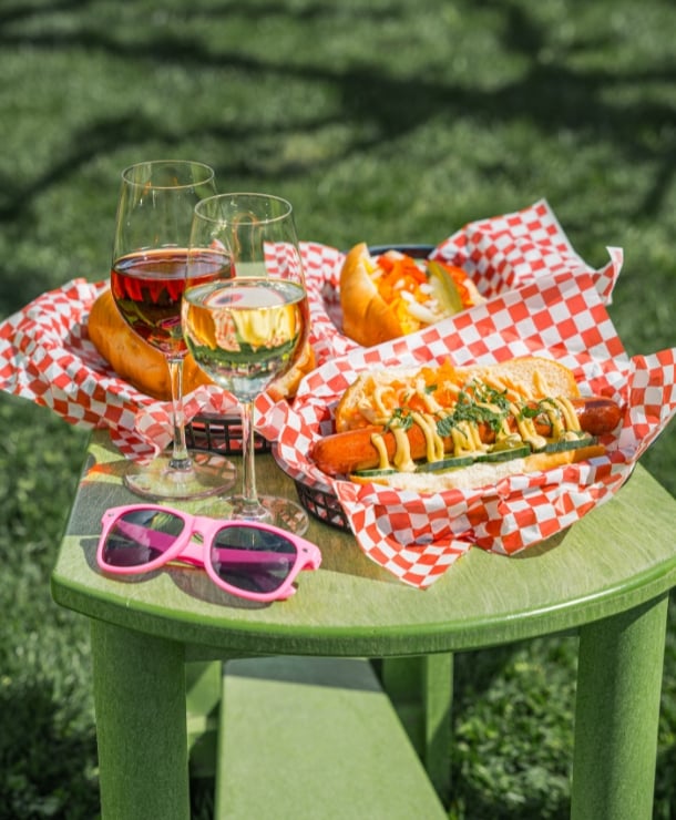 3 loaded hotdogs with 2 glasses of wine and Joie pink sunglasses